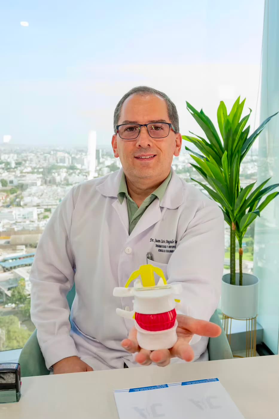 Dr. Juan Carlos Angulo Totesaut sostiene un modelo de disco intervertebral con implante